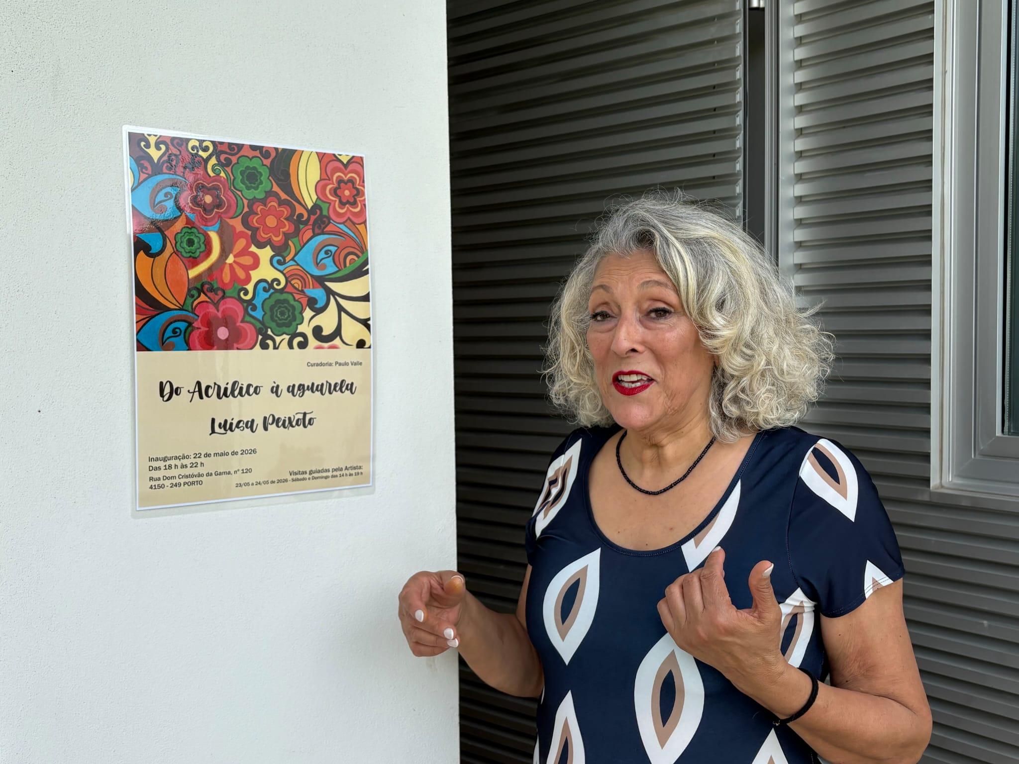 Luísa Peixoto junto ao cartaz da exposição «Do Acrílico à Aguarela», Porto, maio de 2026.